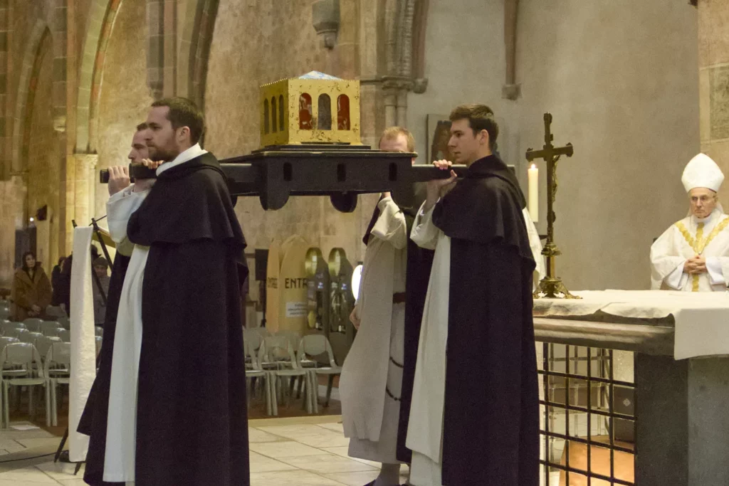 Moines portant une relique dorée lors d'une procession religieuse dans une église