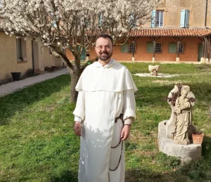 Moine en habit blanc dans la cour d'une abbaye au printemps