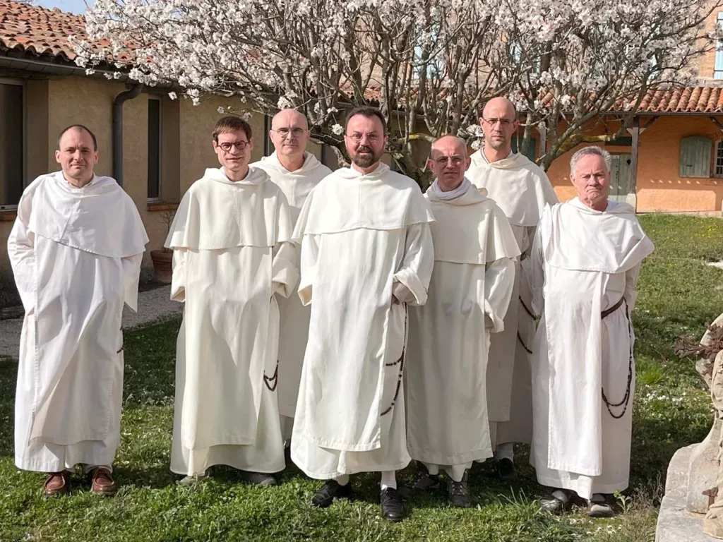 Groupe de moines en habits blancs posant devant un arbre en fleurs